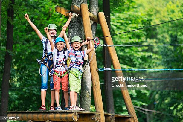 los niños que se divierten en el parque de aventura del curso de cuerdas - leisure activity fotografías e imágenes de stock