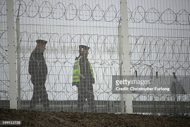 Police officers patrol Security fencing to prevent migrants entering the Port of Calais on September 5, 2016 in Calais, France. Local people and...