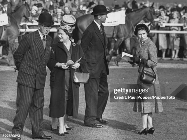 Queen Elizabeth II pictured with Queen Elizabeth the Queen Mother who is speaking to John Verney, 20th Baron Willoughby de Broke in the paddock at...