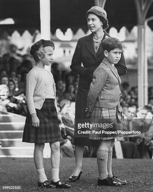 Queen Elizabeth II and her children, Princess Anne and Prince Charles, wait together for the next event in the Braemar Highland Games, Scotland,...