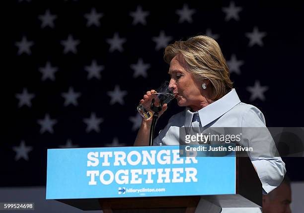 Democratic presidential nominee former Secretary of State Hillary Clinton pauses to take a drink of water to help soothe a cough during a campaign...