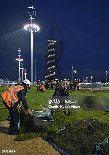 Britain - Workers prepare lawns at Olympic Park in London on the night of July 18 before the opening ceremony of the Olympic Games which will be held...