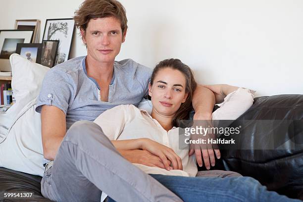 young couple sitting on sofa, portrait - hazel bond stock pictures, royalty-free photos & images