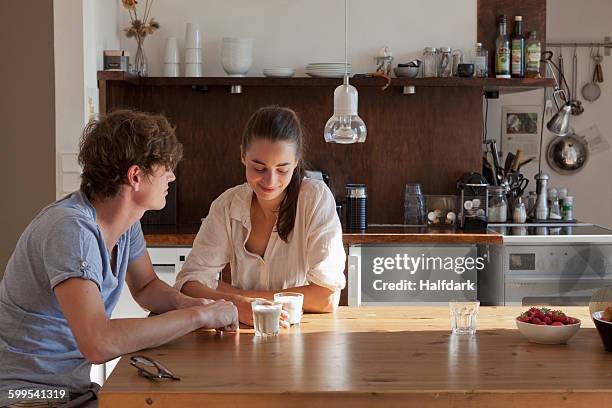 young couple sitting at dining table - sólo con adultos fotografías e imágenes de stock