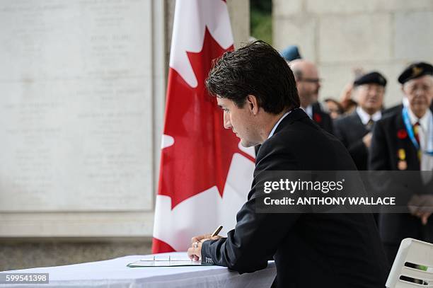 Canadian Prime Minister Justin Trudeau writes a message in the visitors book at the Sai Wan War Cemetery during his visit to Hong Kong on September...