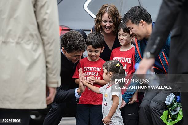 Canadian Prime Minister Justin Trudeau high-fives a young girl outside the Sai Wan War Cemetery during his visit to Hong Kong on September 6, 2016....