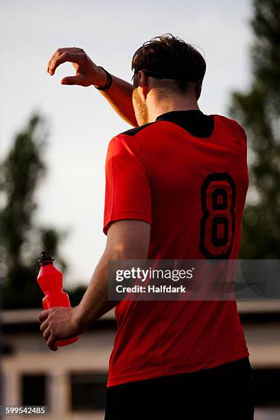 rear view of tired sportsman cleaning sweat on face - maillot de sport photos et images de collection