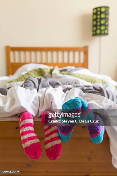young women in bed underneath quilt, socked feet sticking out of bed - protruding stock pictures, royalty-free photos & images