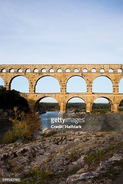 view of pont du gard over gardon river against sky - aqueduct stockfoto's en -beelden