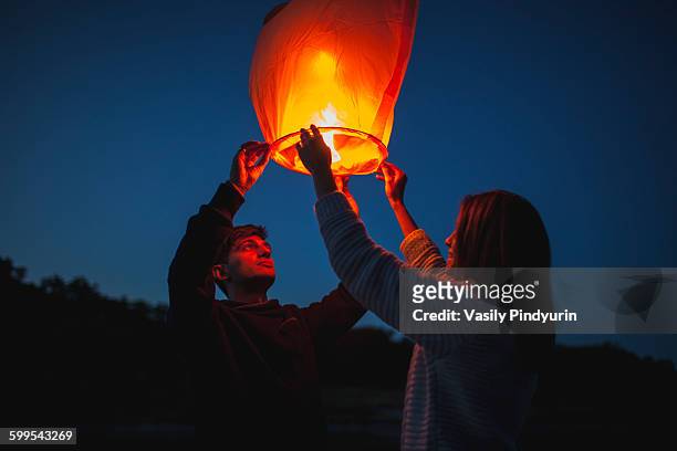 low angle view of hikers releasing paper lanterns - releasing stock-fotos und bilder