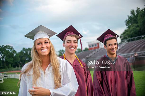 young female and male graduates at graduation ceremony - maroon graduation stock pictures, royalty-free photos & images