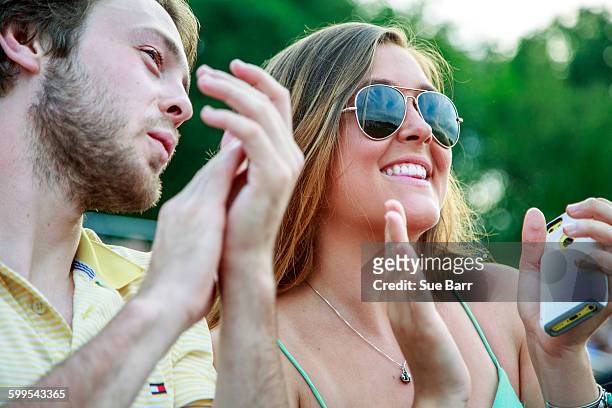 young man and teenage sister clapping at graduation ceremony - sue clapper stock pictures, royalty-free photos & images