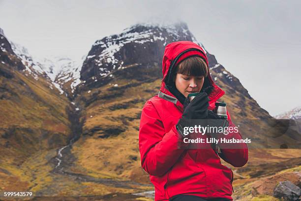 woman drinking coffee against mountain during winter - flask stock pictures, royalty-free photos & images