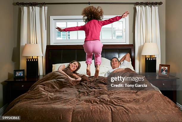 rear view of girl in mid air jumping on parents bed - children jumping bed stock-fotos und bilder
