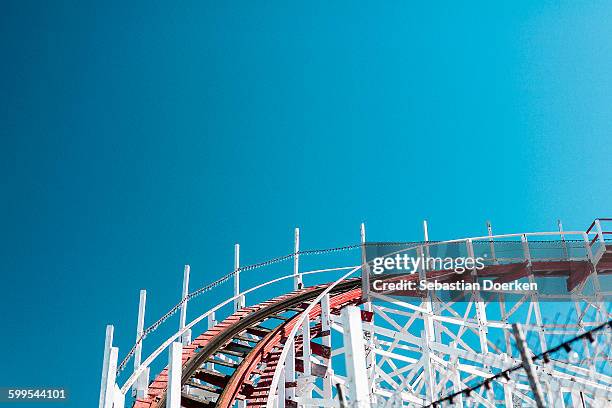 low angle view of roller coaster track against clear blue sky - achtbaan stockfoto's en -beelden