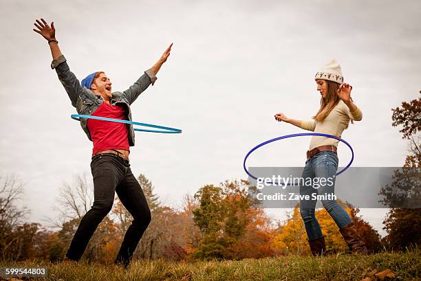 young couple playing with plastic hoops in autumn park - gymnastikreifen stock-fotos und bilder