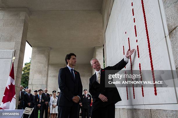 Canadian Prime Minister Justin Trudeau looks at a wall of remembrance with British historian Tony Banham at the Sai Wan War Cemetery during his visit...