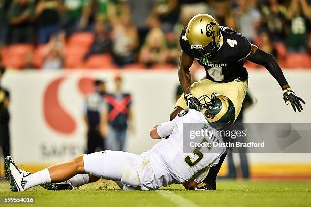 Quarterback Faton Bauta of the Colorado State Rams is tackled by defensive back Chidobe Awuzie of the Colorado Buffaloes as he rushes at Sports...
