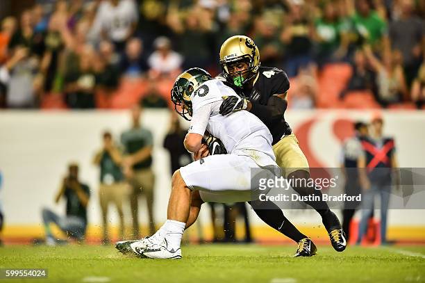 Quarterback Faton Bauta of the Colorado State Rams is tackled by defensive back Chidobe Awuzie of the Colorado Buffaloes as he rushes at Sports...