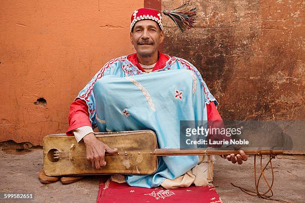 moroccan man playing gimbri, spinning hat tassel - moroccan culture stock pictures, royalty-free photos & images