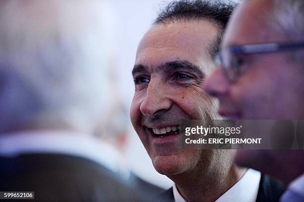 French telecommmunications and media group Altice founder Patrick Drahi stands next to Altice NV group CEO and CEO of SFR Michel Combes before...