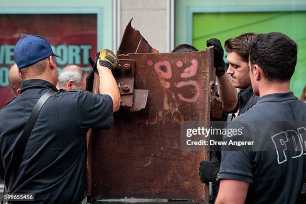 Firefighters from FDNY Engine 54, Ladder 4, Battalion 9 prepare to move a piece of steel from the World Trade Center to a trailer, during a ceremony...