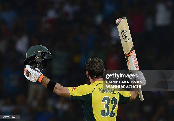 Australia's Glenn Maxwell raises his bat and helmet in celebration after scoring a century during the first T20 international cricket match between...