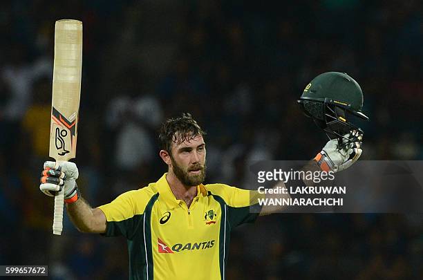 Australia's Glenn Maxwell raises his bat and helmet in celebration after scoring a century during the first T20 international cricket match between...