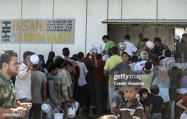 Syrians wait with their buckets as The Foundation for Human Rights and Freedoms And Humanitarian Relief gives hot meal at Martyrs Square as the...