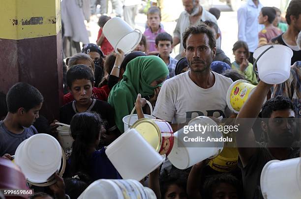 Syrians wait with their buckets as The Foundation for Human Rights and Freedoms And Humanitarian Relief gives hot meal at Martyrs Square as the...