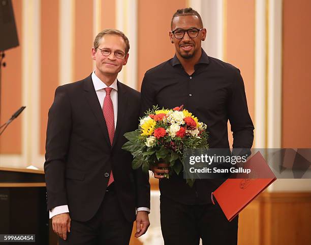 Bayern Munich football star Jerome Boateng poses with the 2016 Moses Mendelssohn Award after receiving it from Berlin Mayor Michael Mueller on...