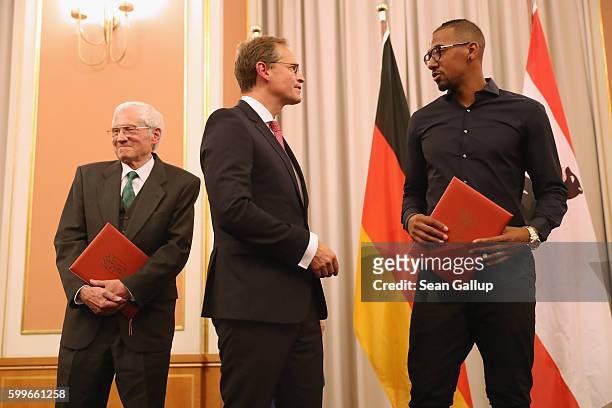 Bayern Munich football star Jerome Boateng and Peter von der Osten-Sacken hold with their awards while chatting with Berlin Mayor Michael Mueller at...