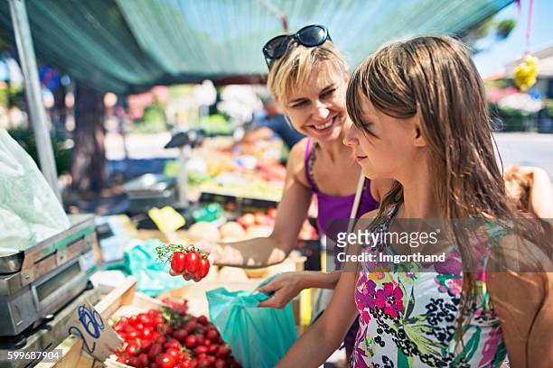 mother and daughter buying tomatoes at the italian farmer's market - colorful vegetables summer stock pictures, royalty-free photos & images