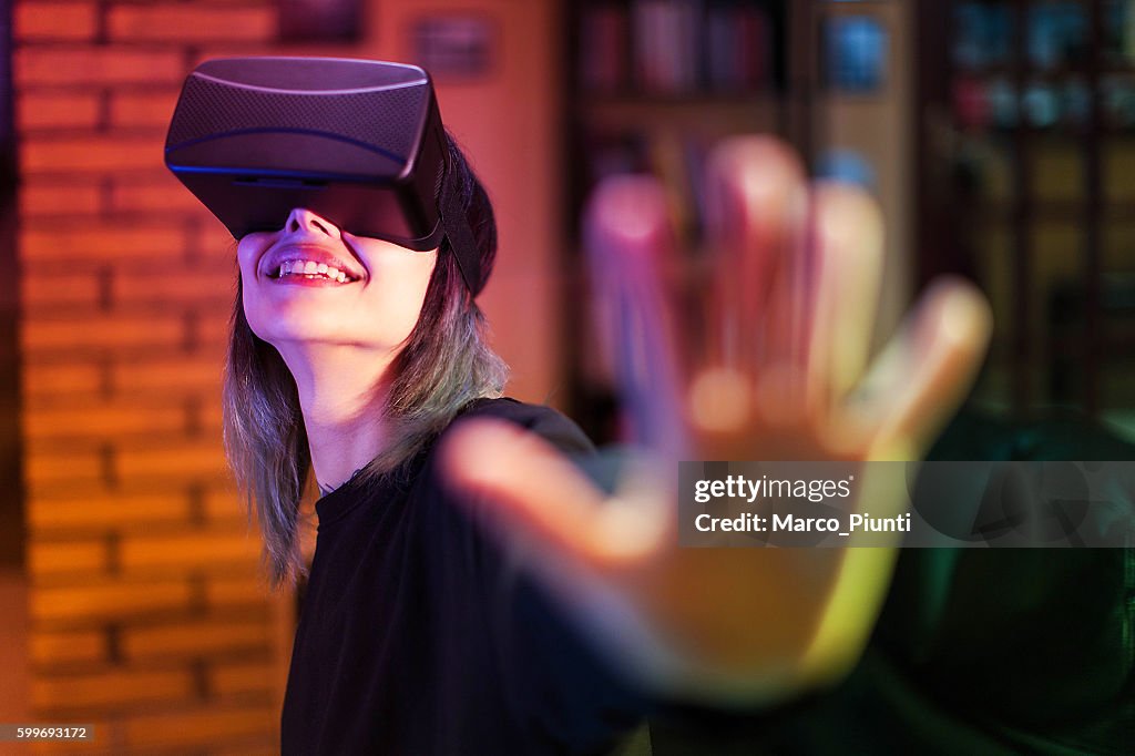 Young woman looks fascinated into Virtual Reality Headset