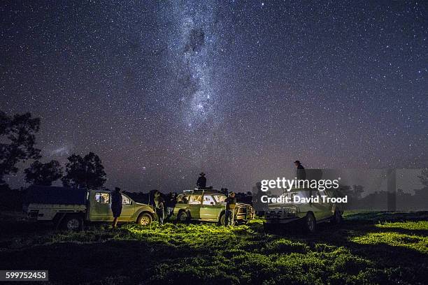 group of men with four wheel drives look at stars - explore australia foto e immagini stock