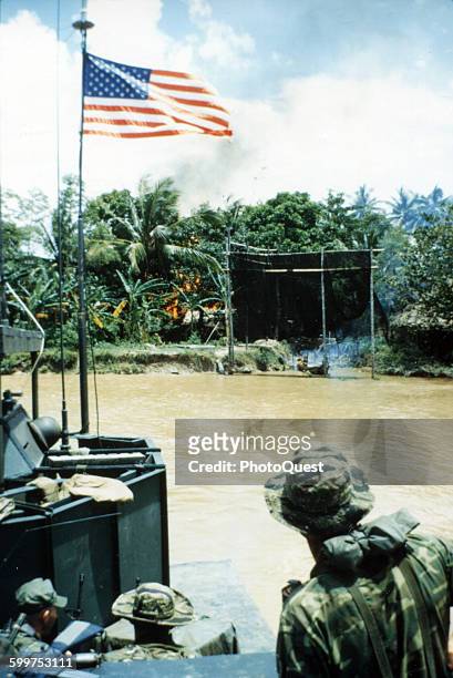 Heavily armed 'Mike' boat carrying members of a US Navy SEAL team departs the site of a Viet Cong fortification on the Bassac River which was...