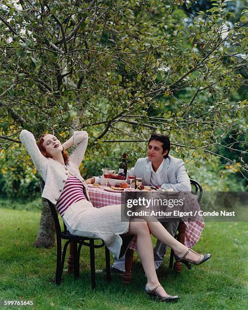 Redhead model, Karen Elsen, in Marc Jacobs pale-pink tweed Peter Pan collar jacket and pencil skirt with cashmere candy-striped tank, sitting having...