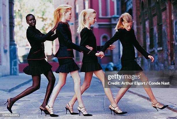 Four models crossing street, wearing tailored jackets and pleated skirts CREDIT MUST READ: Arthur Elgort/Conde Nast via Getty Images.