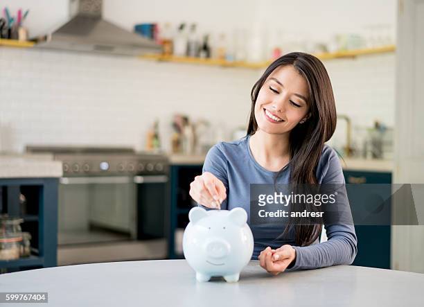 mujer ahorrando dinero en una alcancía - ahorro fotografías e imágenes de stock