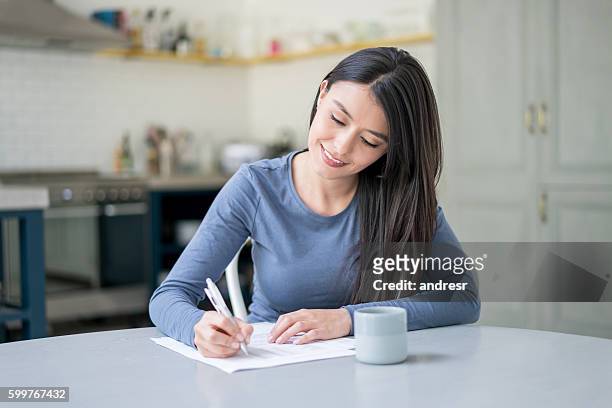 casual woman at home writing on documents - woman signing stock pictures, royalty-free photos & images