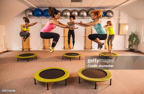 gruppe von frauen, die während des pilates-übungsunterrichts auf trampolinspringen springen. - trampoline jump stock-fotos und bilder
