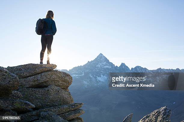 female hiker stands on summit, looks out to mtns - 石柱 ストックフォトと画像