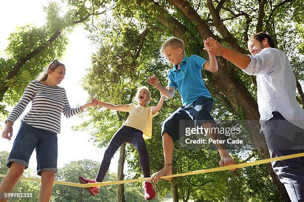 family playing on slackline in park - two kids playing with hose stock-fotos und bilder
