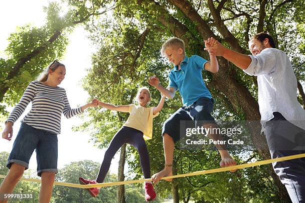 family playing on slackline in park - slackline stockfoto's en -beelden