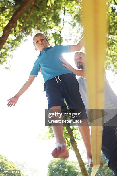 father helping son on slackline - slackline stock-fotos und bilder