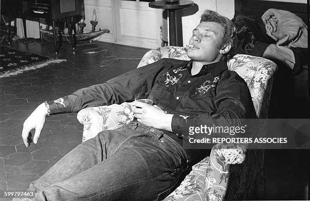 Johnny Hallyday se repose un verre à la main en France, circa 1960 .