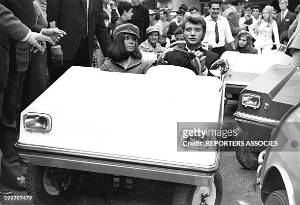 Johnny Hallyday conduit une petite voiture en compagnie d'une amie à Paris, France, circa 1960 .