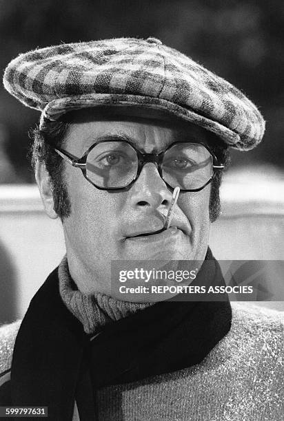 Acteur Tony Curtis avec une casquette, des lunettes, une écharpe et un thermomètre dans la bouche sur le tournage d'un film, circa 1960, en France .