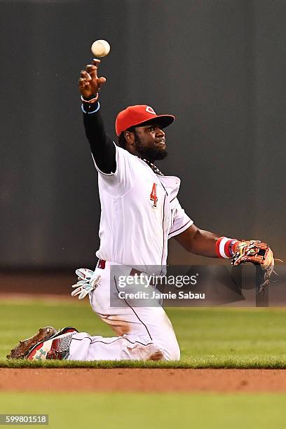 Brandon Phillips of the Cincinnati Reds makes the throw from his knees after making a diving stop of a ground ball in the ninth inning against the...