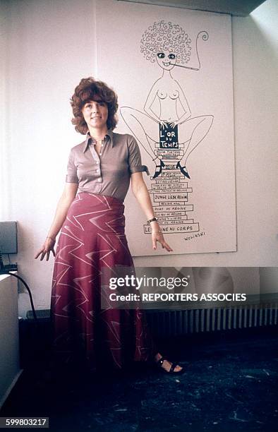 Portrait de l'écrivain et éditrice Régine Deforges en France, circa 1960 - Au mur, une affiche de Wolinski 'L'Or du temps', la maison d'édition...